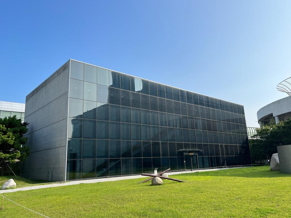 Arquitetura do Espaço Lee Ufan, com paredes de concreto e uma pedra no jardim